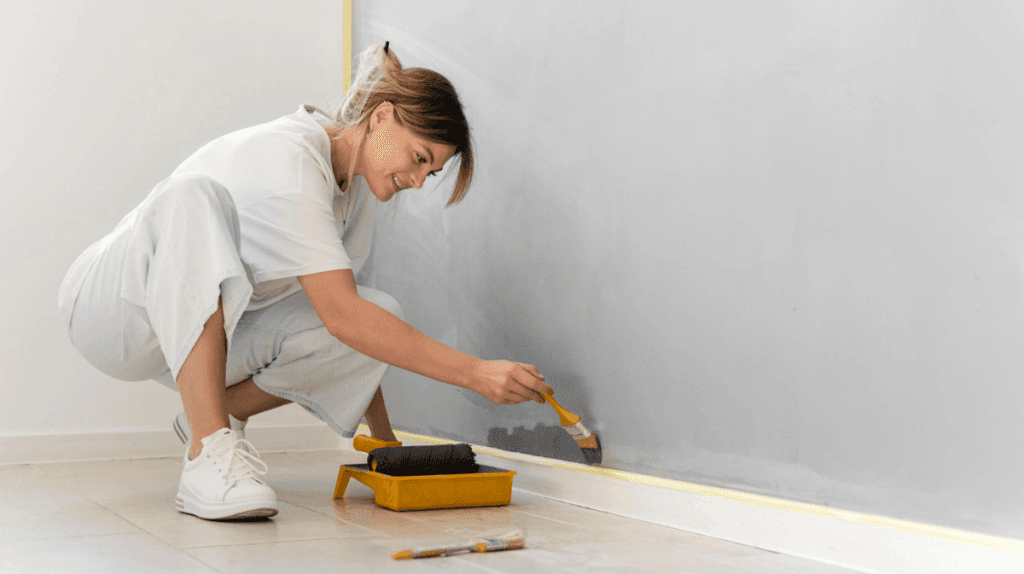 Femme qui peint un mur avec des plinthes